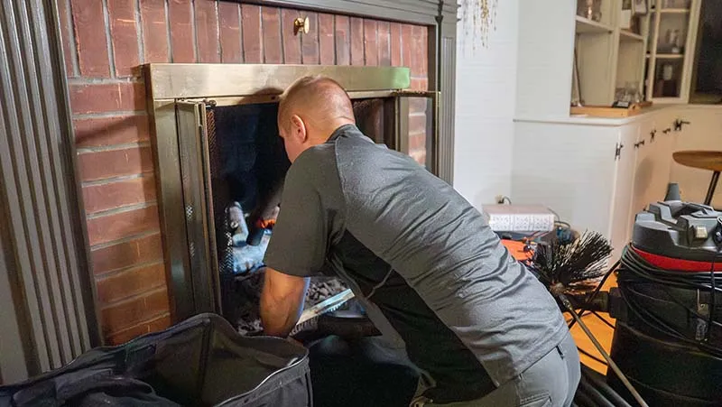 Sioux Falls homeowner inspecting fireplace damper for safety